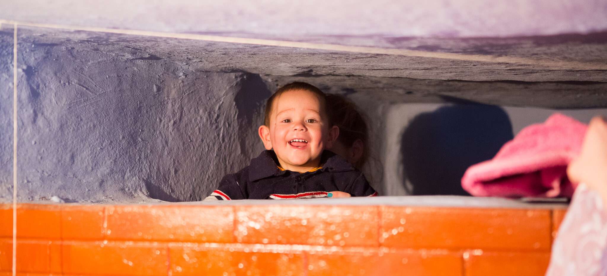 Child in Moldova behind an orange wall